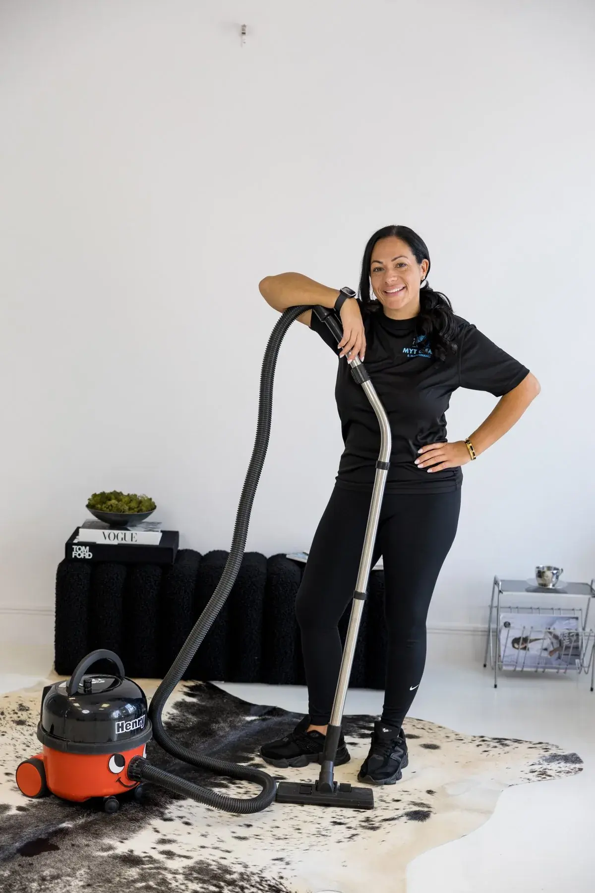 A MyT Clean cleaner in a branded polo shirt with a commercial vacuum